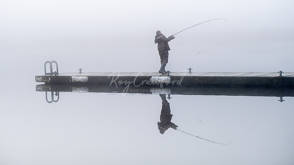 Fisherman casting in the mist